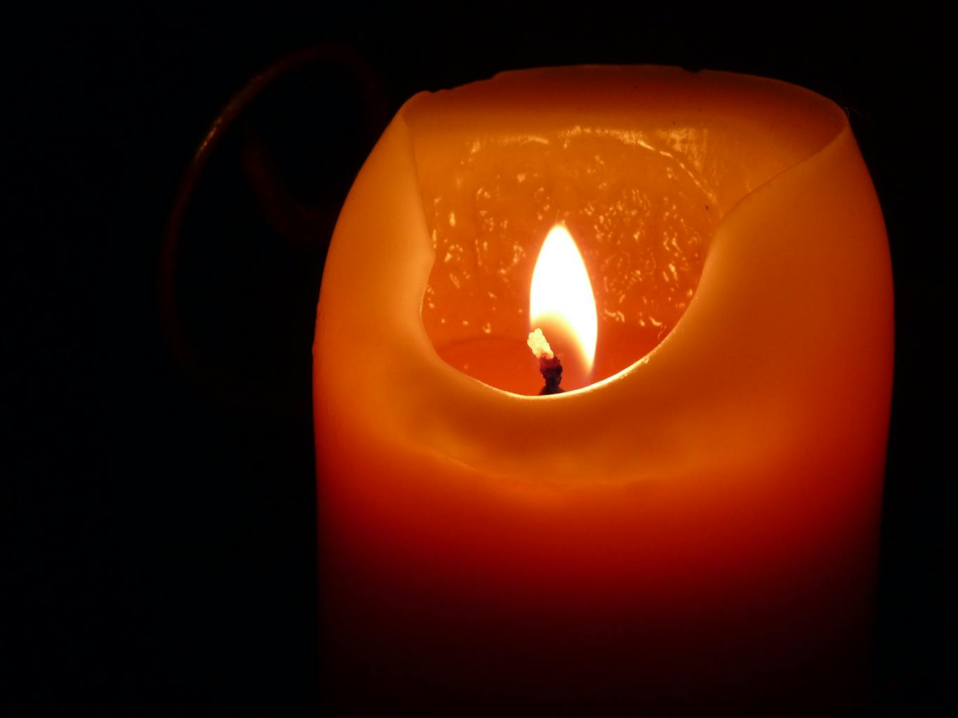 A close-up shot of a candle flame illuminating the darkness with its warm glow.