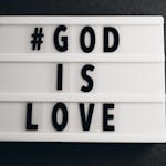 Lightbox with the message '#GOD IS LOVE' on a gray background, inspirational text.