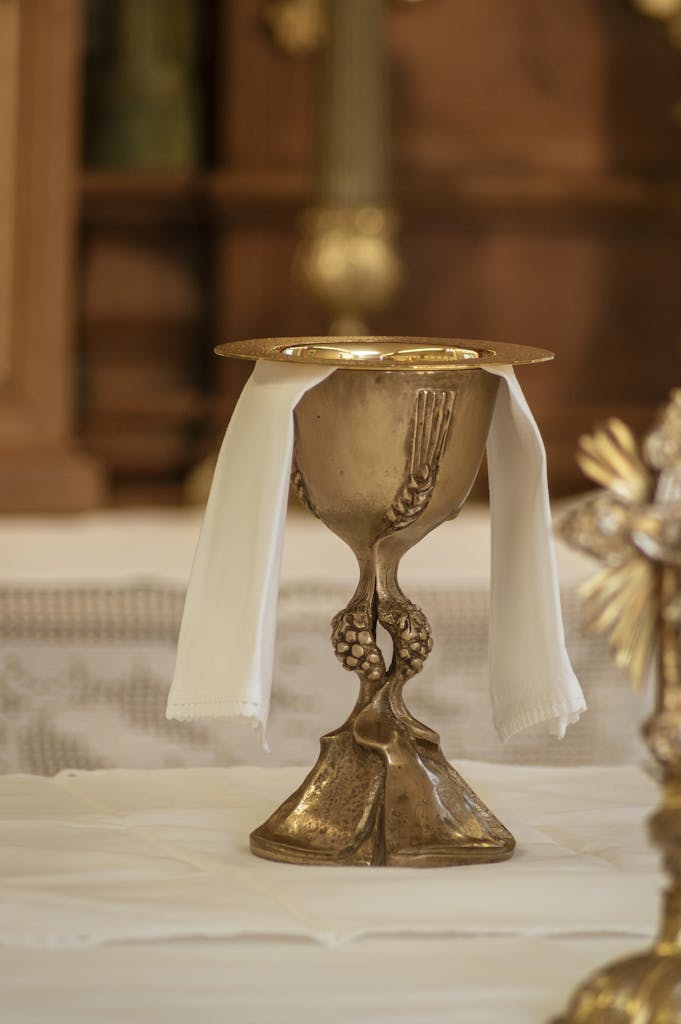 Close-up of a golden chalice with white cloth on a church altar, symbolizing Catholicism.