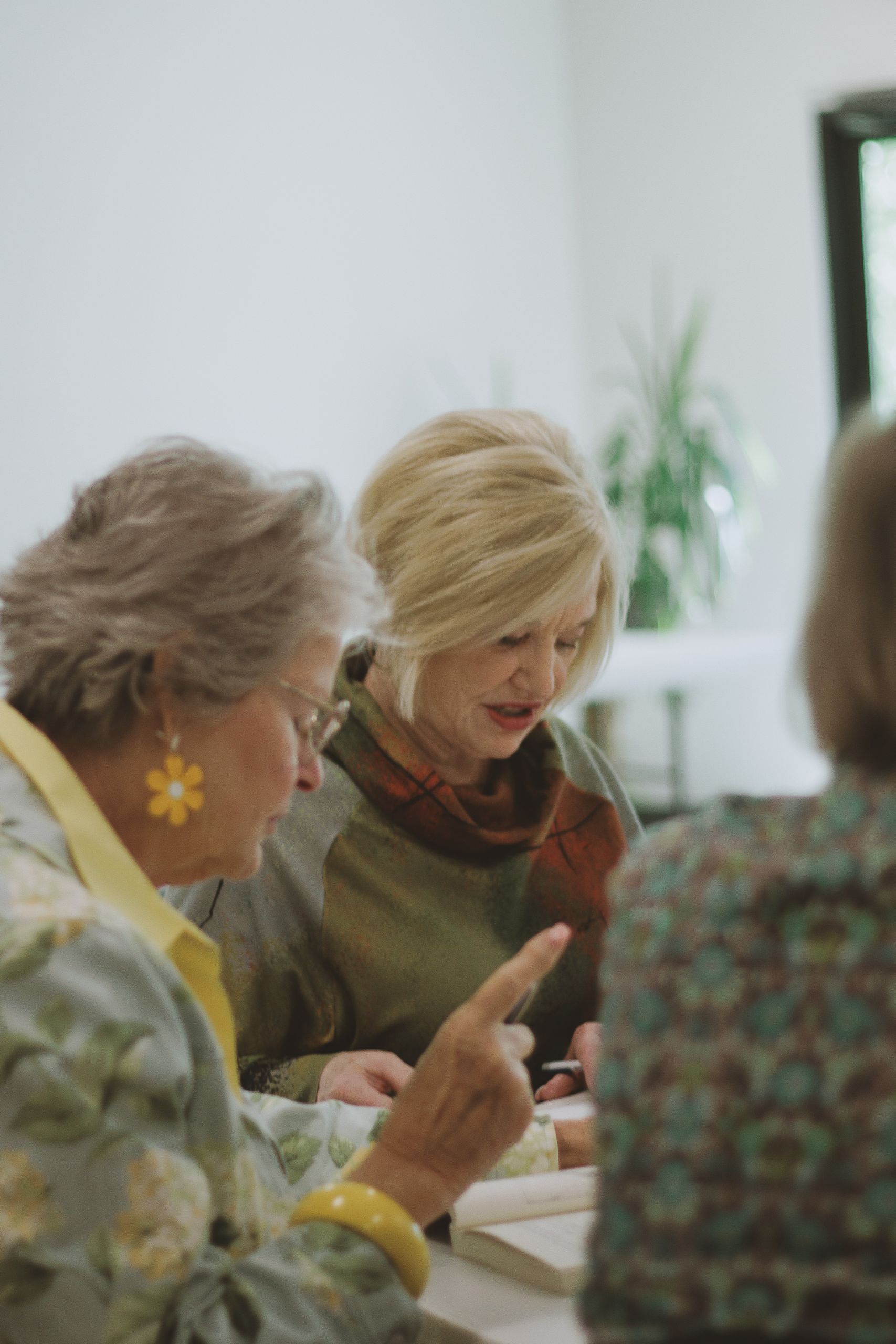 A group of women engages in a bible study in a welcoming interior space.